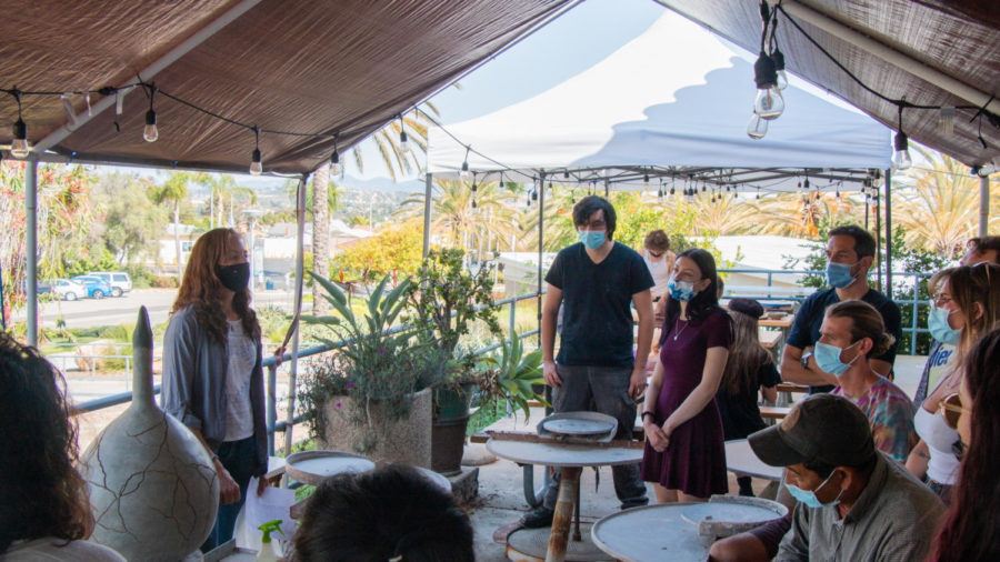 The class stands in the outdoor area of the ceramics class as Maggie Skidmore presents the larger of her two “crackpots”.